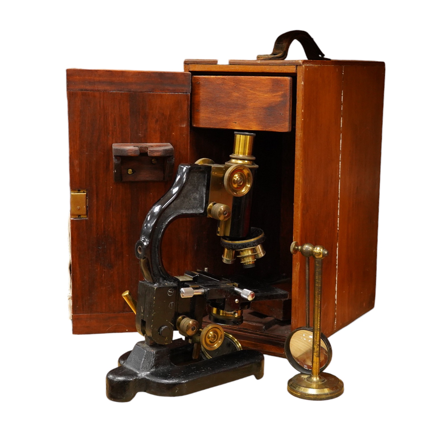 An early 20th century pine and plywood cased microscope by C.Baker, London, containing an integral drawer with alternative lenses, and a magnifying glass on a brass stand, the case dimensions; 38cm high, 18cm wide, 27.5c